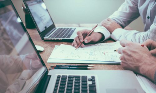 Business professional analyzing tax reports and spreadsheets on a computer in a clean office environment.